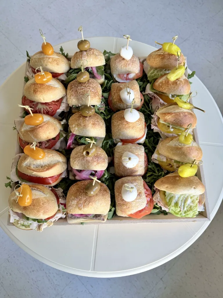 Top-down view of a ready-to-serve sandwich platter tray filled with artisan rolls and standard sandwiches